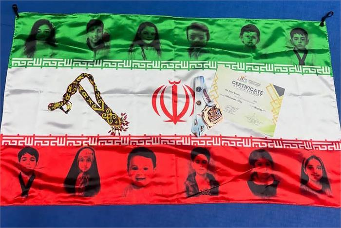 اقدام زیبای زهرا رحیمی به یاد کودکان شهید و مظلوم جنگ تحمیلی ۱۲ روزه/ پرچمی منقش به تصاویر فرزندان ایران